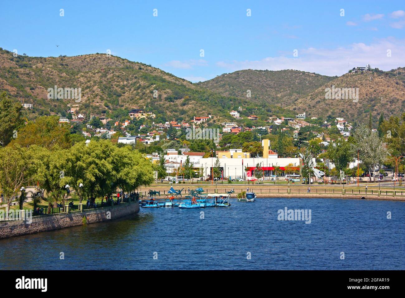 VILLA CARLOS PAZ, CORDOBA, ARGENTINA la città in una giornata di sole. Il lago di San Roque in primo piano e le colline sullo sfondo. Foto Stock