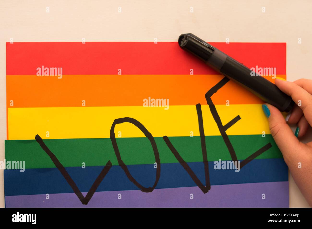 L'AMORE scritto a mano con un pennarello nero su uno sfondo colorato della bandiera dell'arcobaleno, simbolo lgbt Foto Stock