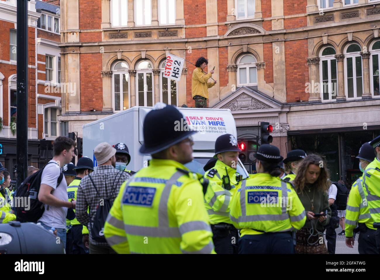 Cambridge Circus, Londra, Regno Unito. 24 agosto 2021. I manifestanti del cambiamento climatico provenienti dalla ribellione di estinzione che protestava a Cambridge Circus , bloccando Charing Cross Road lungo la strada per Trafalgar Square. L'attivista sale in cima al furgone bianco. Credit: Xiu Bao/Alamy Live News Foto Stock