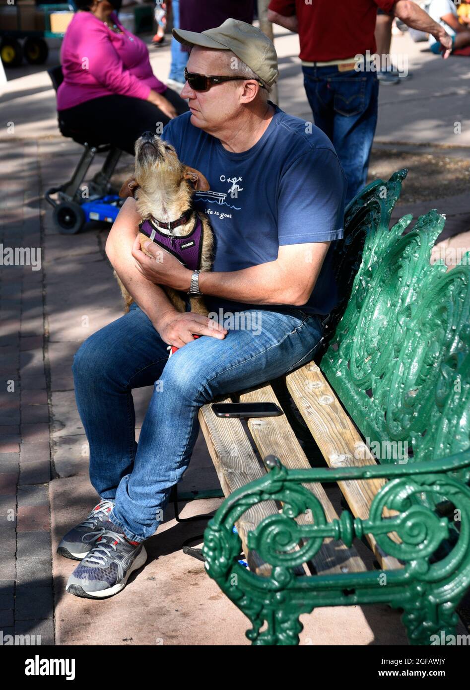 Un uomo si rilassa con il suo cane da compagnia su una panchina in un parco pubblico a Santa Fe, New Mexico. Foto Stock