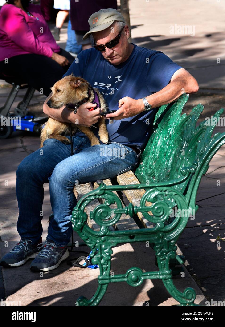 Un uomo si rilassa con il suo cane da compagnia su una panchina in un parco pubblico a Santa Fe, New Mexico. Foto Stock