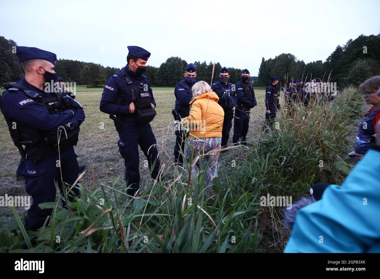 Il MP Katarzyna Kretkowska è visto tentare di camminare oltre un cordong di polizia per raggiungere un gruppo di rifugiati afghani bloccati al confine a Usnarz Gorny, Polonia il 24 agosto 2021. Per 16 giorni di fila 32 rifugiati afghani sono rimasti bloccati al confine tra Polonia e Bielorussia senza cibo o rifugio. Le autorità polacche negano che i migranti abbiano mai raggiunto il suolo polacco in contrasto con i rapporti di individui locali che hanno dichiarato che il gruppo è stato spinto indietro dalle guardie di frontiera. Nell'agosto di quest'anno sono stati segnalati quasi 3000 rifugiati che tentavano di attraversare la frontiera e che in tutto il 2020 erano stati obbligati a meno di 100 rifugiati. Th Foto Stock