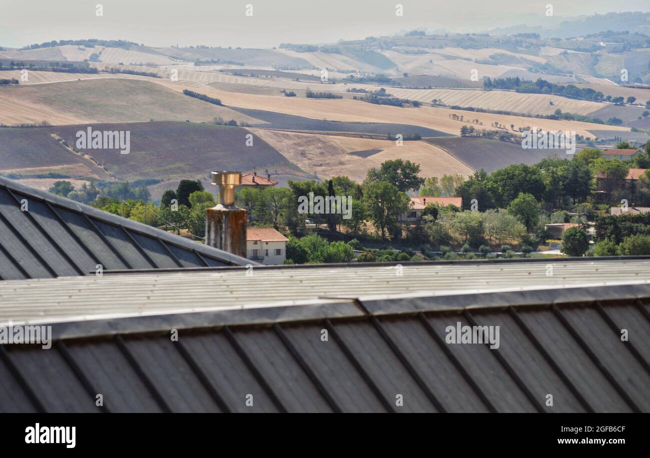 il tetto di un edificio industriale e colline coltivate sullo sfondo Foto Stock