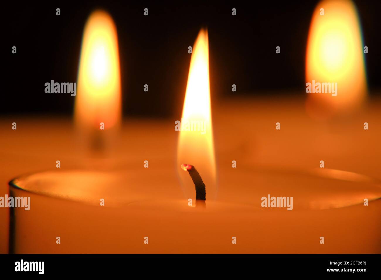 Primo piano candela fiamma. . candele bianche. Candele che bruciano al buio. Foto Stock