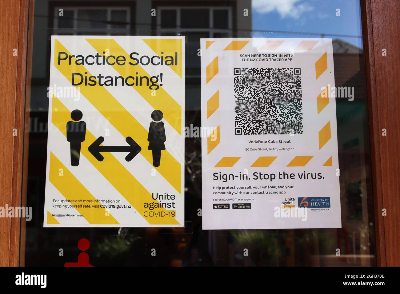 Wellington, Nuova Zelanda, 25 agosto 2021. Ufficiale Covid-19 social distancing poster e Covid Tracer contatto tracciatura codice QR segno nella finestra di un negozio a Wellington, chiuso a causa del rigido livello 4 Lockdown. Credit: Lynn Grieveson/Alamy Live News Foto Stock