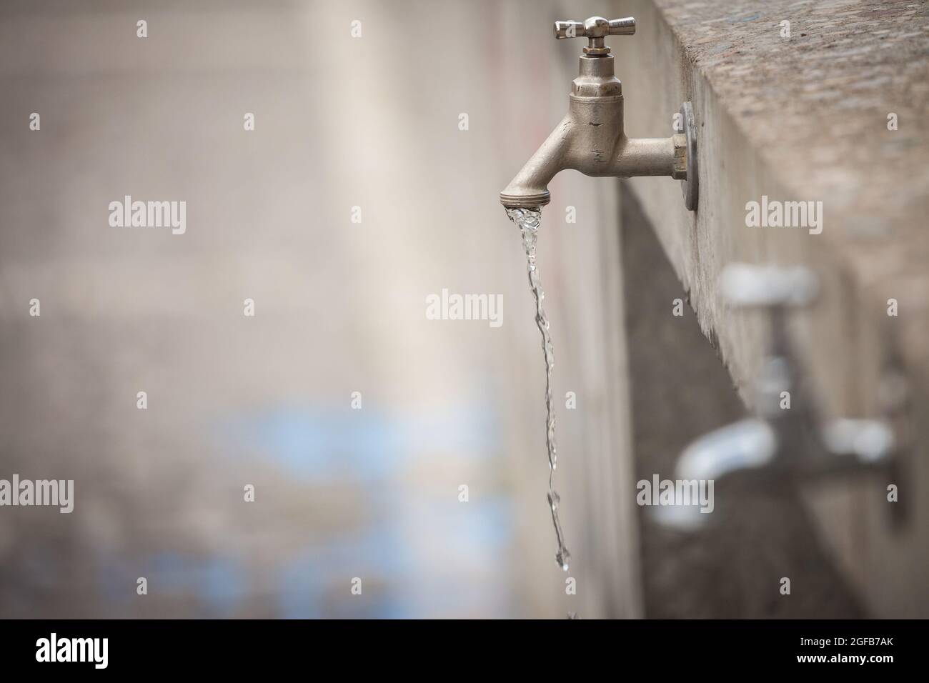 Immagine di un rubinetto che perde con acqua che viene sprecata, gocciolando dal rubinetto. Foto Stock