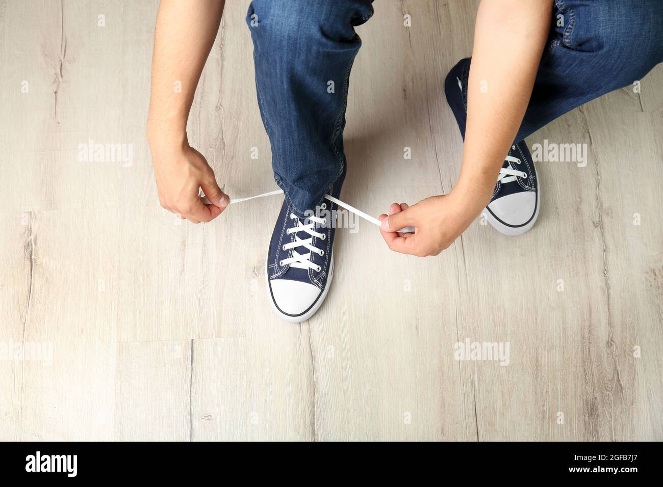 Uomo che lega le scarpe si aggrada su parquet di legno Foto stock - Alamy