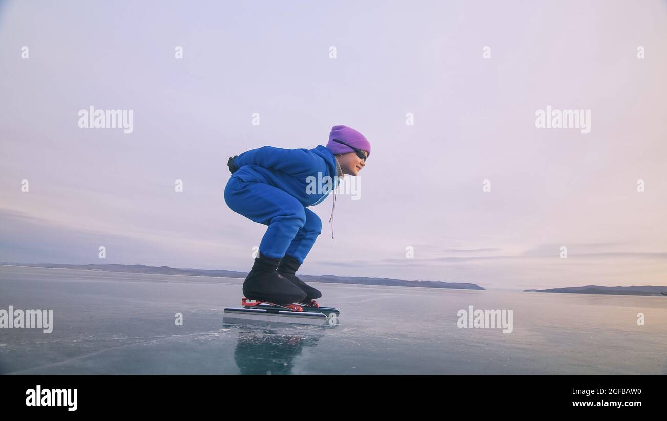 Il bambino allenarsi sul pattinaggio di velocità sul ghiaccio. L'atleta  all'inizio, in una posizione sportiva. La bambina pattina in inverno in abbigliamento  sportivo, occhiali sportivi Foto stock - Alamy