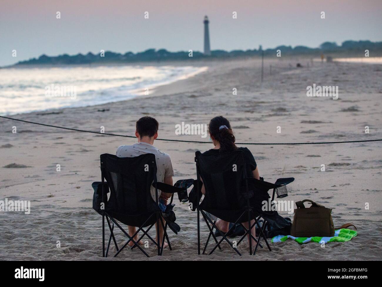 Cape May, Stati Uniti. 24 agosto 2021. Una coppia guardò il sole tramonta martedì 24 agosto 2021 su Cove Beach a Cape May, New Jersey. L'ondata di calore sugli Stati Uniti orientali continua oggi con alti nella gamma più bassa di 90 gradi con un sacco di aria umida. ( Credit: William Thomas Cain/Alamy Live News Foto Stock