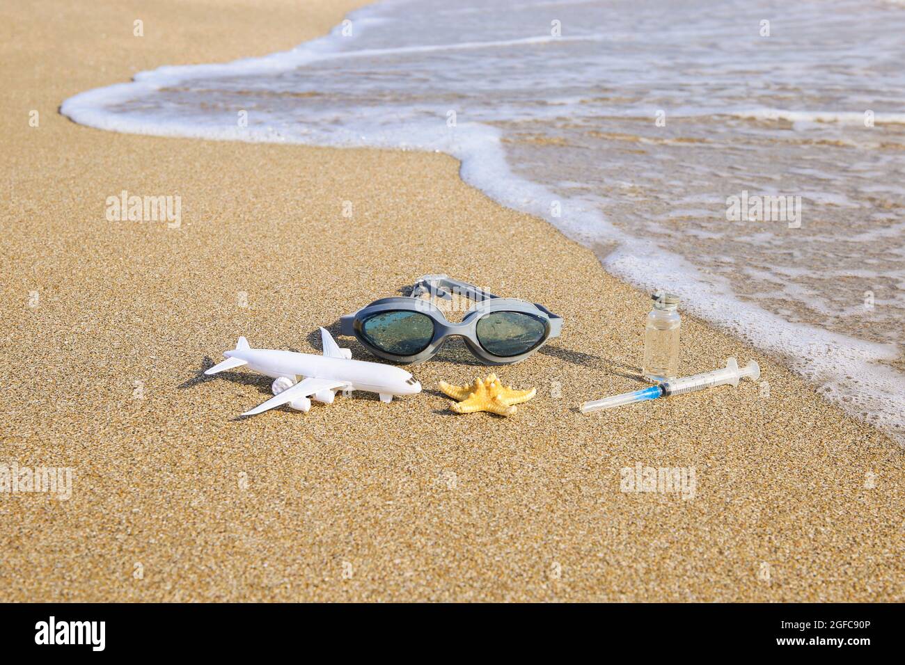 Vaccino contro Covid-19, siringa, occhiali da immersione e stelle marine in spiaggia. Foto Stock