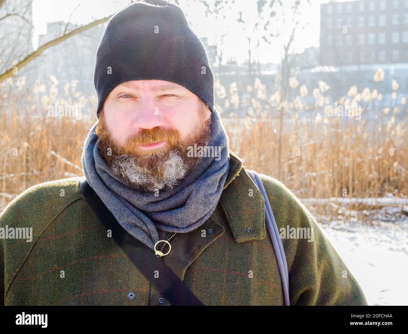 Ritratto all'aperto di uomo europeo adulto in inverno. Uomo bearded che si distende sulla passeggiata di inverno nella foresta nevosa, cattura candid, scena di lifestyle Foto Stock