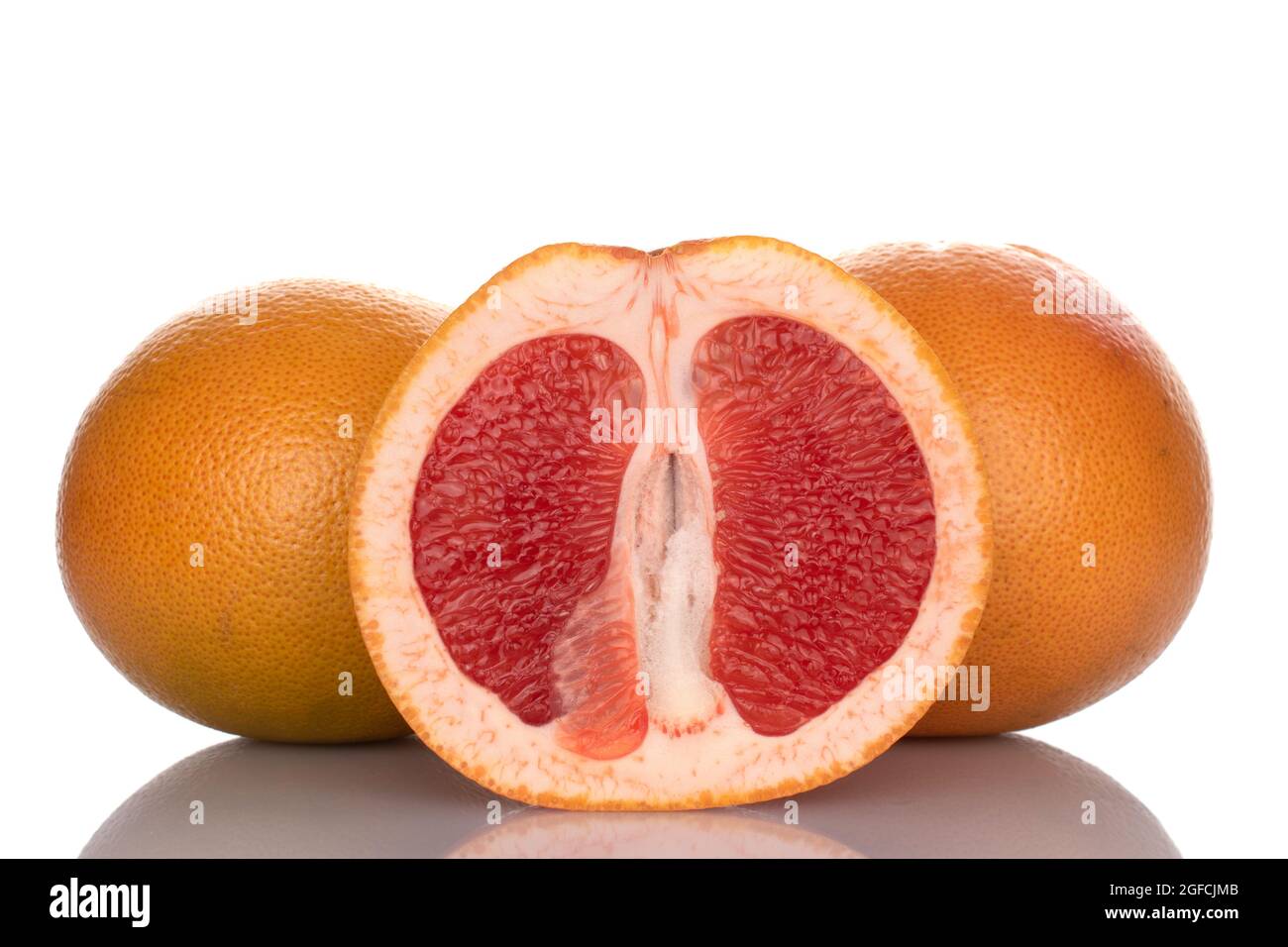 Metà e due pompelmi succosi maturi interi, da vicino, isolati su bianco. Foto Stock
