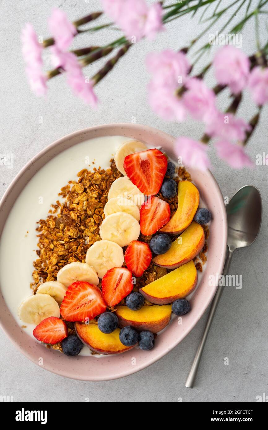 Deliziosa colazione sana, granola con yogurt e frutta dolce, banana e fragola, mirtillo e pesca Foto Stock