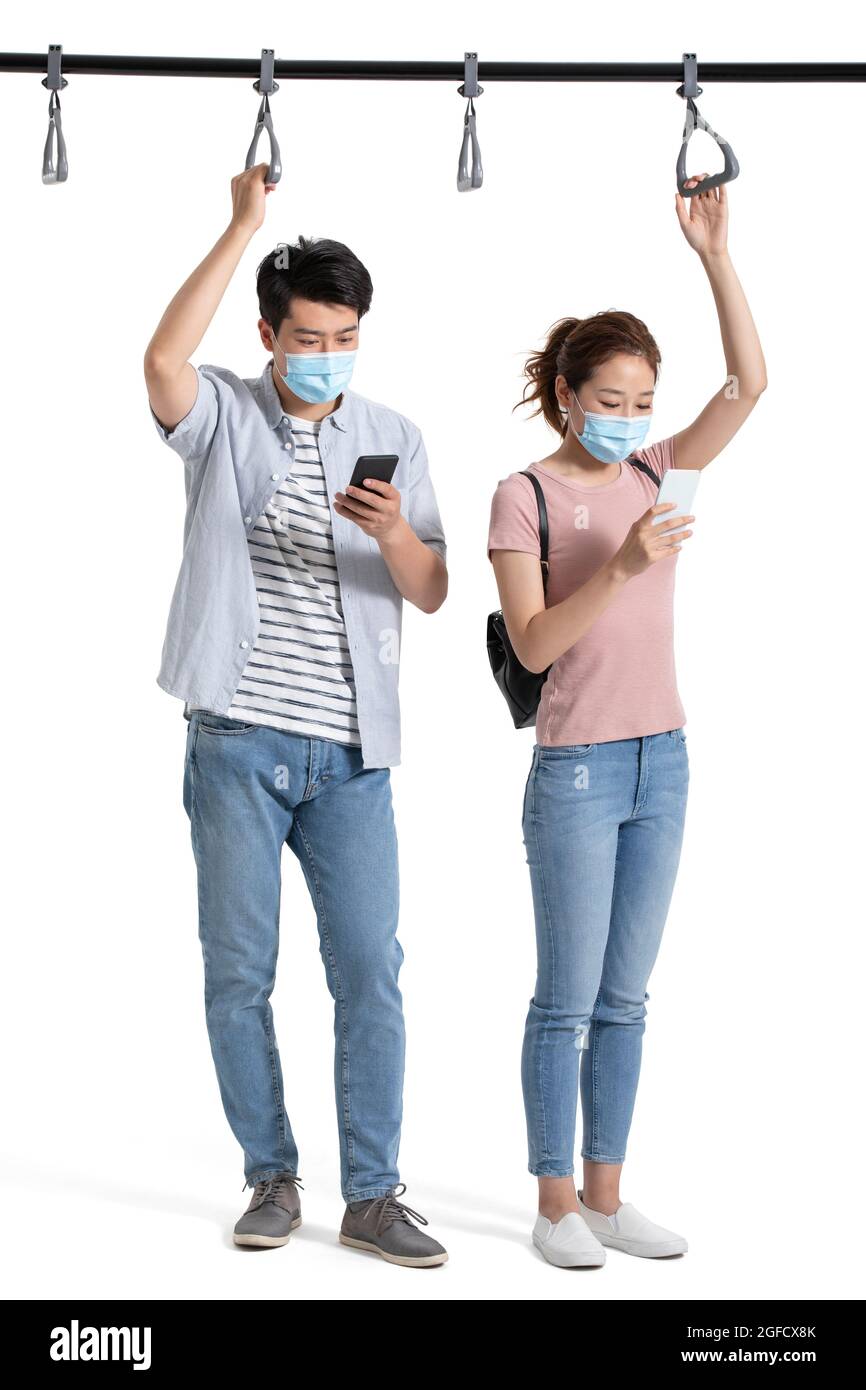 Giovane coppia con maschera chirurgica utilizzando smartphone in metropolitana Foto Stock