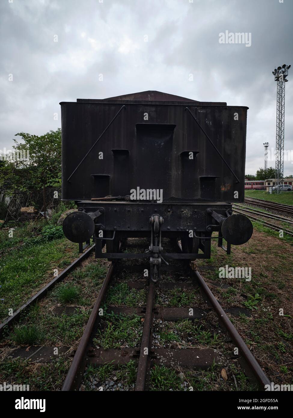 Vecchio vagone ferroviario nero sui binari in uno storico deposito ferroviario di Bratislava, in Slovacchia, sotto un cielo nuvoloso Foto Stock
