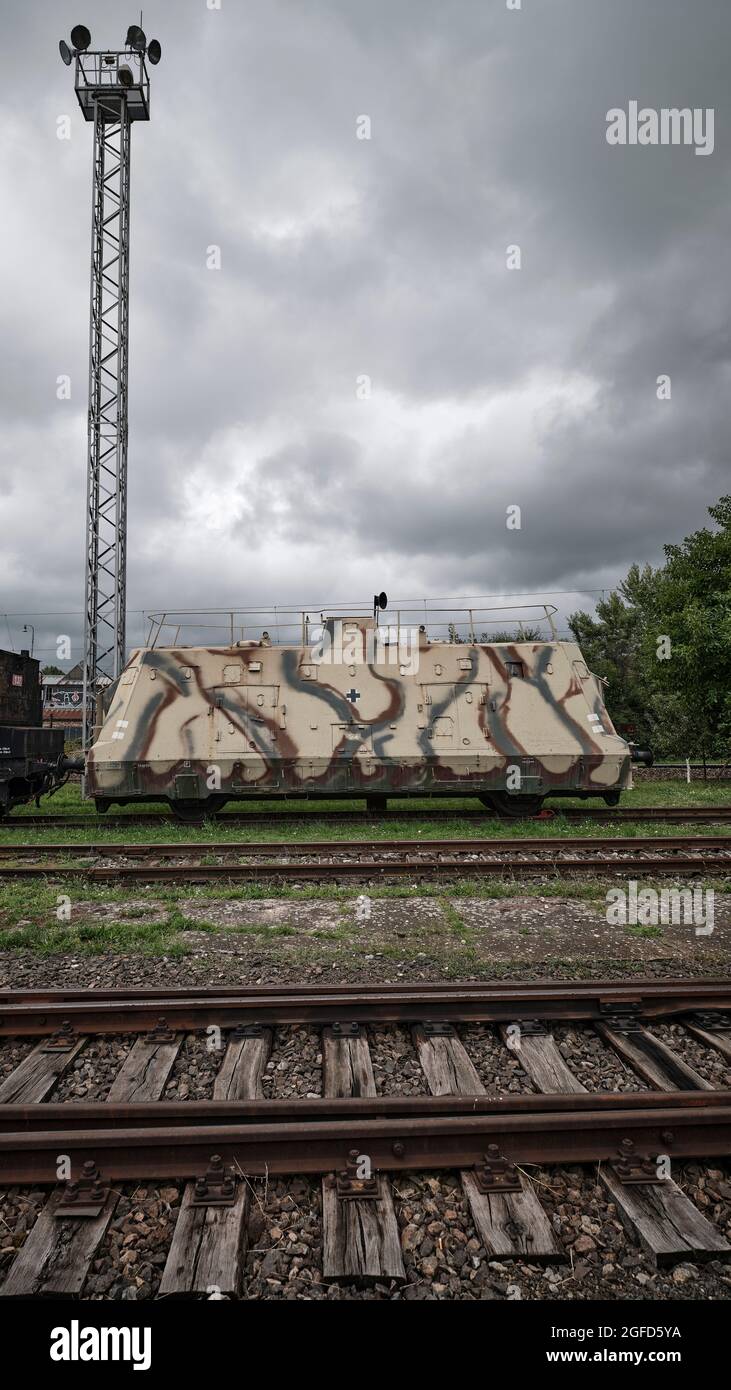 Vagone militare mimetizzato in uno scalo ferroviario sotto spettacolari nuvole di tempesta. Foto Stock