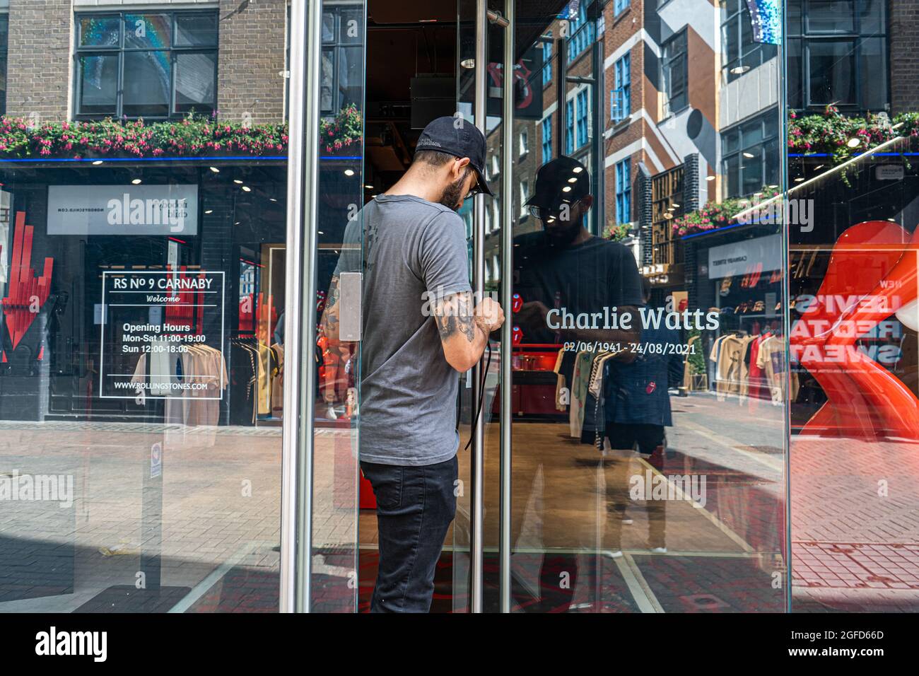 CARNABY STREET LONDRA, REGNO UNITO. 25 agosto 2021. Un assistente di negozio posiziona un nastro nero all'ingresso del negozio Rolling Stones a Carnaby Street come omaggio al batterista Rolling Stones Charlie Watts, morto all'età di 80 anni martedì. Credit amer Ghazzal/Alamy Live News Foto Stock