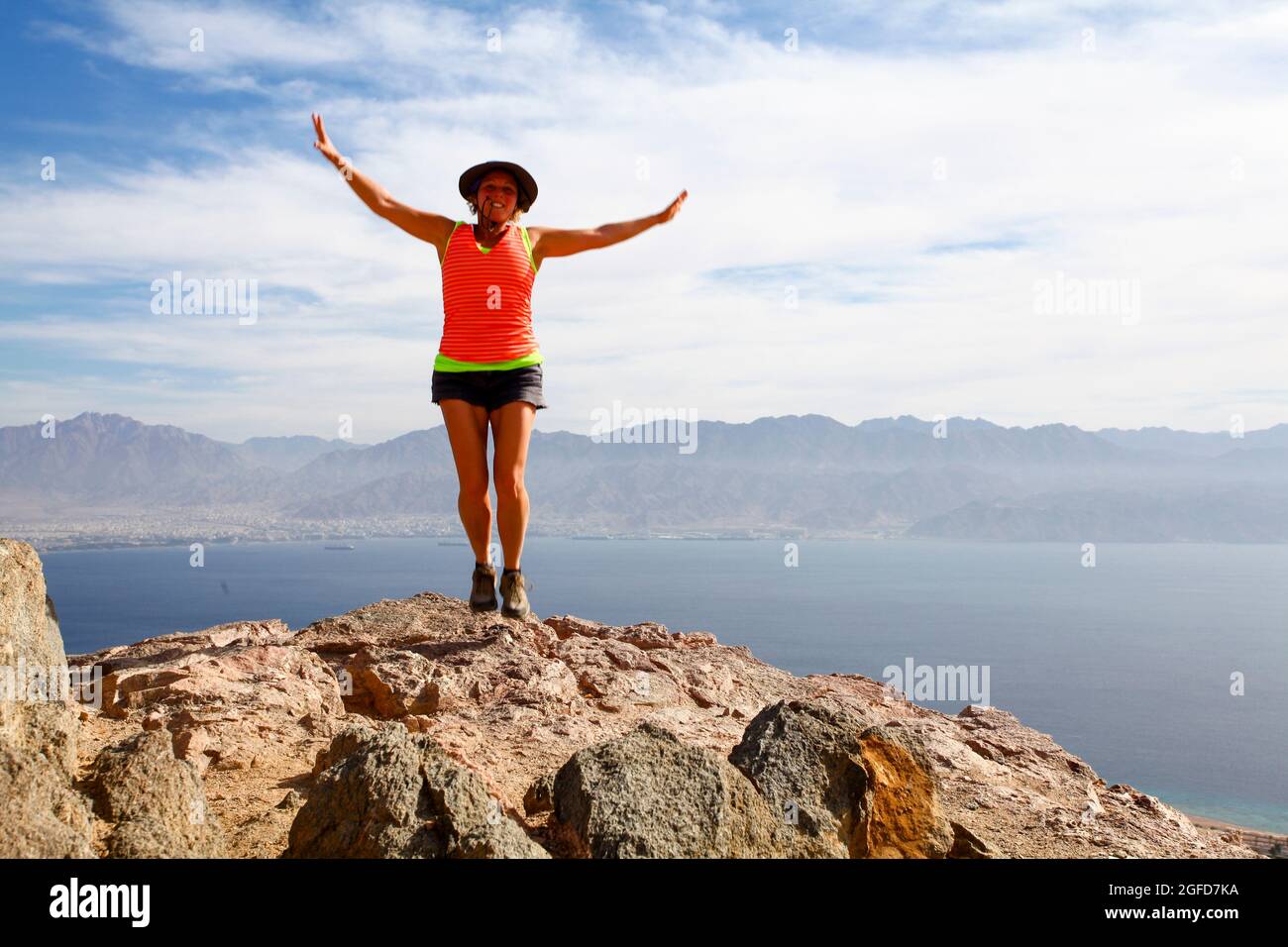L'escursionista femmina celebra il suo successo raggiungendo la vetta delle colorate montagne Eilat Foto Stock