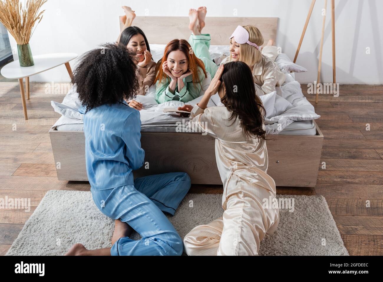 gruppo di donne multietniche sorridenti che parlano durante il partito di sonno Foto Stock