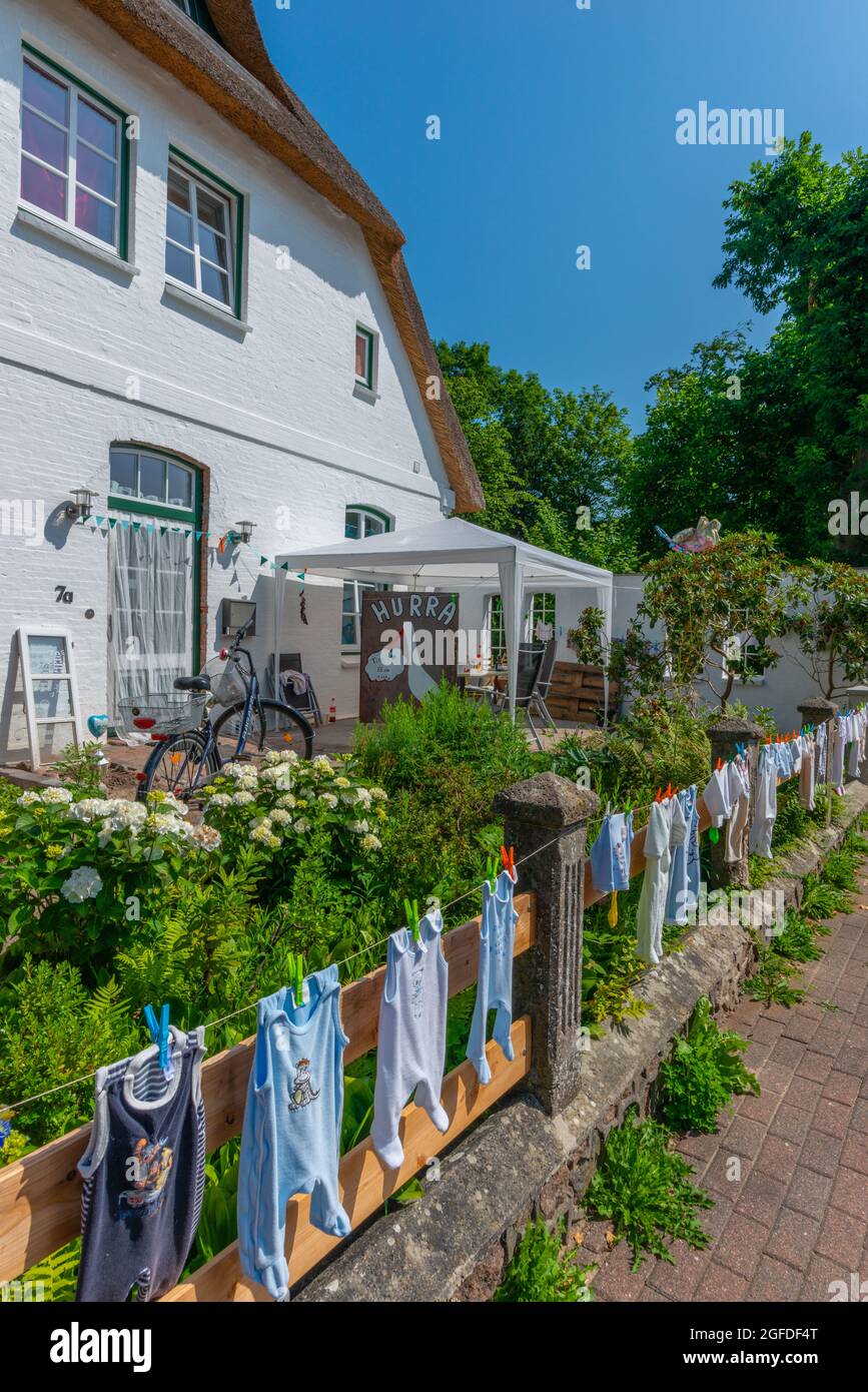 Appendere i vestiti del bambino sulla linea di lavaggio nel giardino anteriore è un vecchio traditon nel clountryside, Süderstapel, Schleswig-Holstein, Germania del nord Foto Stock