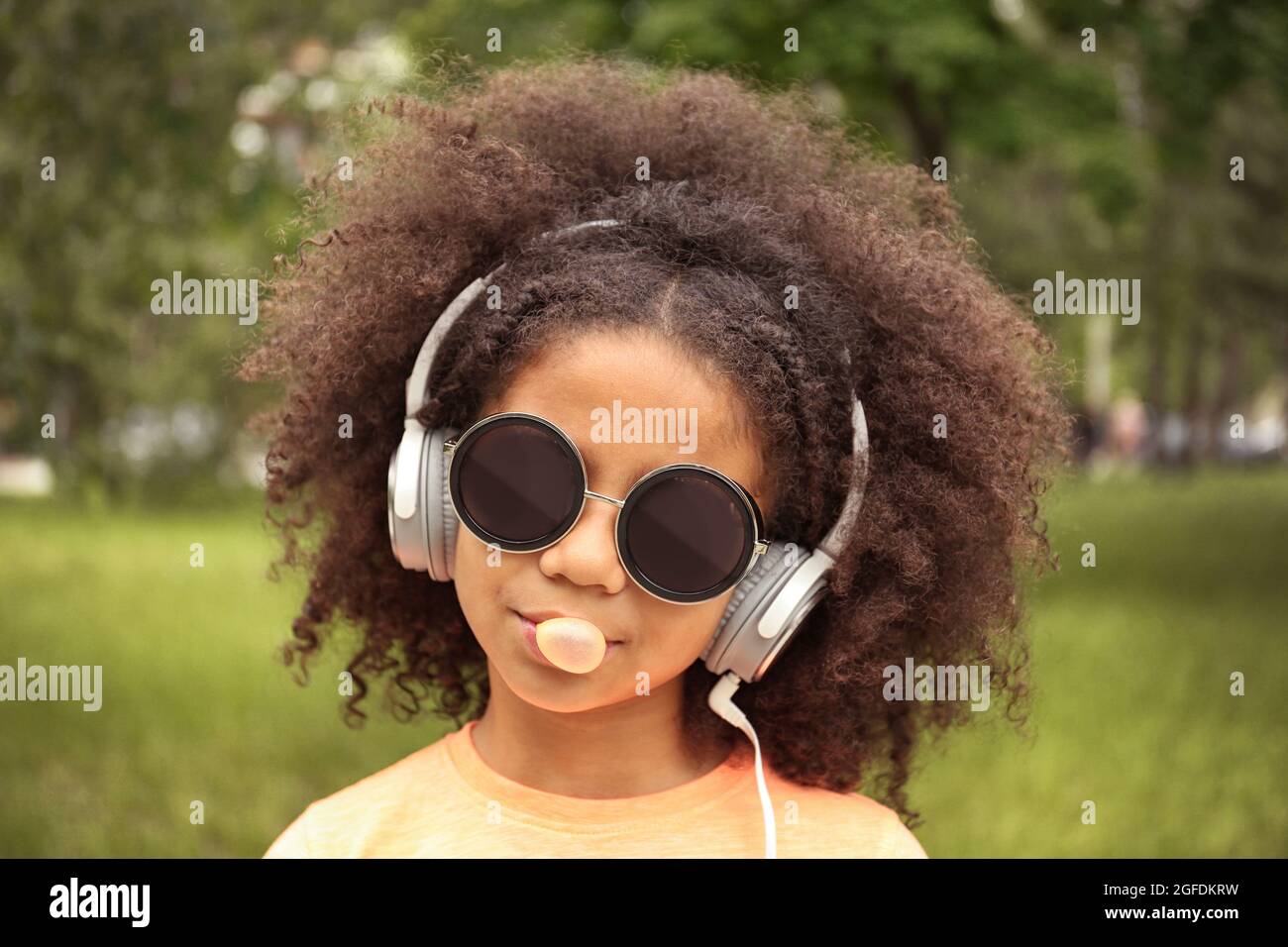 Afro-americani bambina con occhiali da sole e le cuffie chewing bubblegum  in posizione di parcheggio Foto stock - Alamy