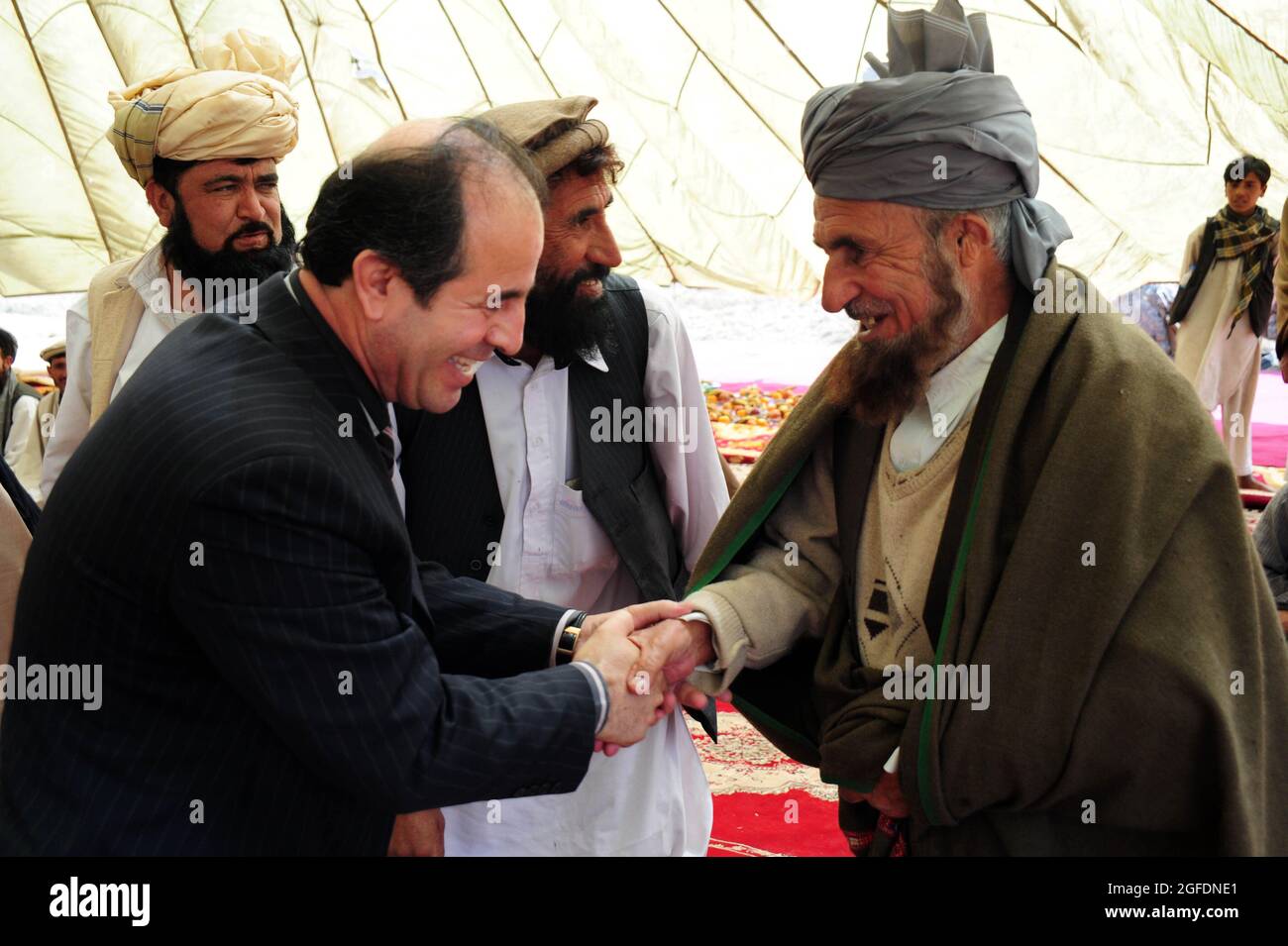 Il generale dell'esercito afghano di Nationl Wasi scuote la mano di un anziano di villaggio marzo 17, nel villaggio di Sorkh-AB, nel distretto di Muhammed Aga, provincia di Logar, Afghanistan. Il governatore si presenta alla shura per parlare della liberazione dell'ex comandante talebano. Foto Stock