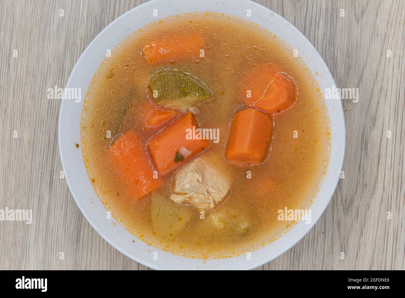 Abbondante ciotola di zuppa di pollo con grandi pezzi di carote e carne per un pasto completo. Foto Stock
