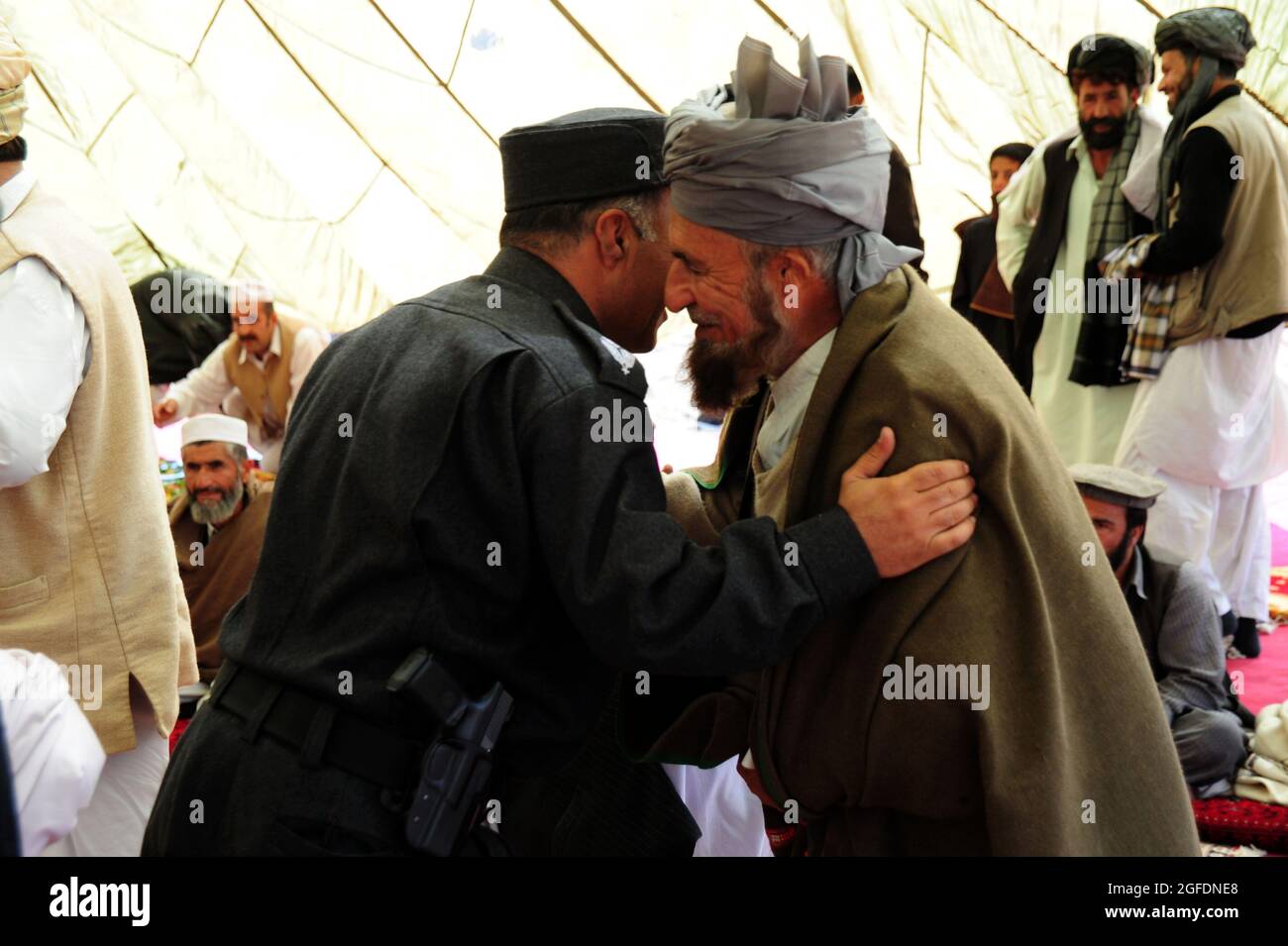 Un comandante della polizia nazionale afghana saluta gli anziani del villaggio marzo 17, nel villaggio di Sorkh-AB, nel distretto di Muhammed Aga, provincia di Logar, Afghanistan. Il comandante saluta tutti prima della festa. Foto Stock