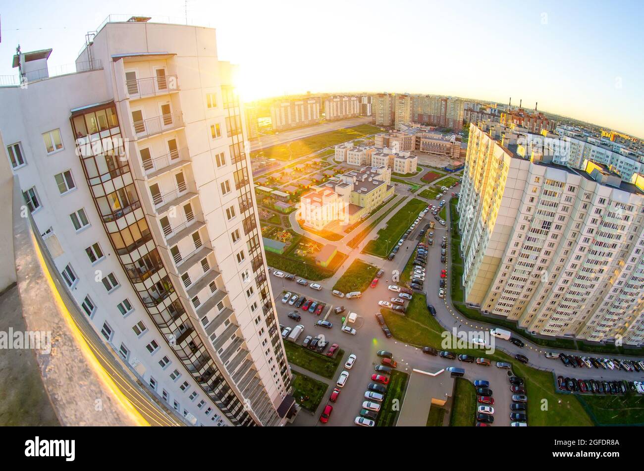 Vista dall'alto del balcone al tramonto e sul cortile del paesaggio cittadino con auto e parcheggio Foto Stock