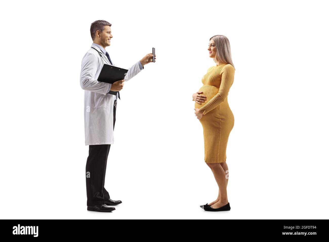 Medico di sesso maschile che mostra un telefono cellulare a una giovane donna incinta isolato su sfondo bianco Foto Stock
