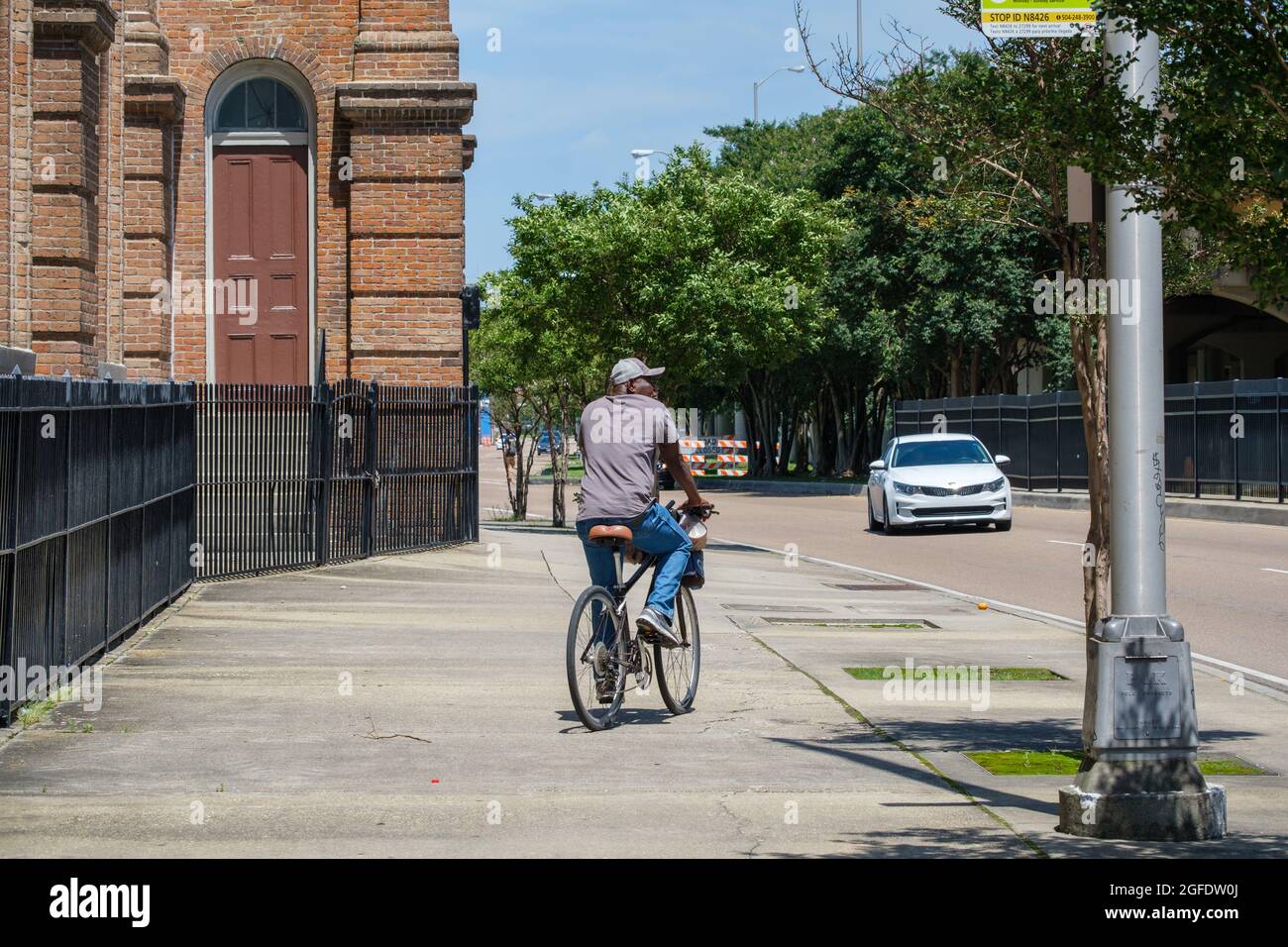 NEW ORLEANS, LA, Stati Uniti d'America - 22 MAGGIO 2021: Bicyclist che cammina sul marciapiede piuttosto che sulla strada nel quartiere di Central City Foto Stock