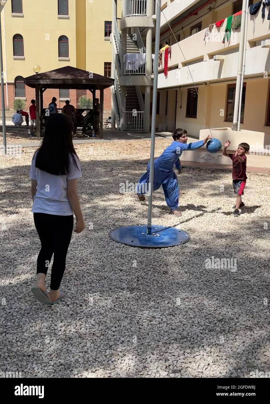 210824-N-NO291-1001 STAZIONE AERONAVALE DI SIGONELLA, ITALIA (AGOSTO 24, 2021) U.S. Navy Sailor gioca la palla di tetherball bambini afghani evacuati alla Naval Air Station Sigonella, 24 agosto 2021. NAS Sigonella sostiene la missione del Dipartimento della Difesa “operazione Allees Refuge” per facilitare la partenza e il trasferimento in sicurezza dei cittadini statunitensi, dei beneficiari di visti speciali per l’immigrazione e delle popolazioni afghane vulnerabili provenienti dall’Afghanistan. (STATI UNITI Foto Navy di Capt. Kevin Pickard, Jr.) Foto Stock