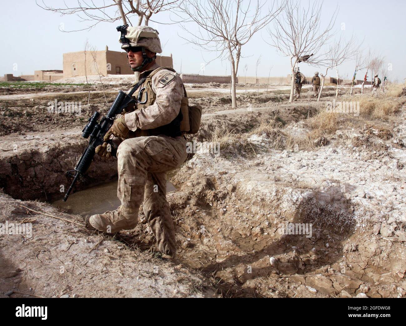 Gunnery Sgt. Troy W. Gans, sergente platoon per la squadra combinata Anti-Armor 1, Weapons Company, 1° Battaglione, 3° Regiment Marino, cammina attraverso un canale di irrigazione a secco Feb 14 durante una pattuglia con Marines di Charlie Co., 1/3. Durante la pattuglia, Marines ha fatto il loro primo contatto con gli anziani del villaggio nell'area dei cinque punti prima di inginarsi con i combattenti talebani. Gans, 34 anni, è di Temecula, California. Foto Stock