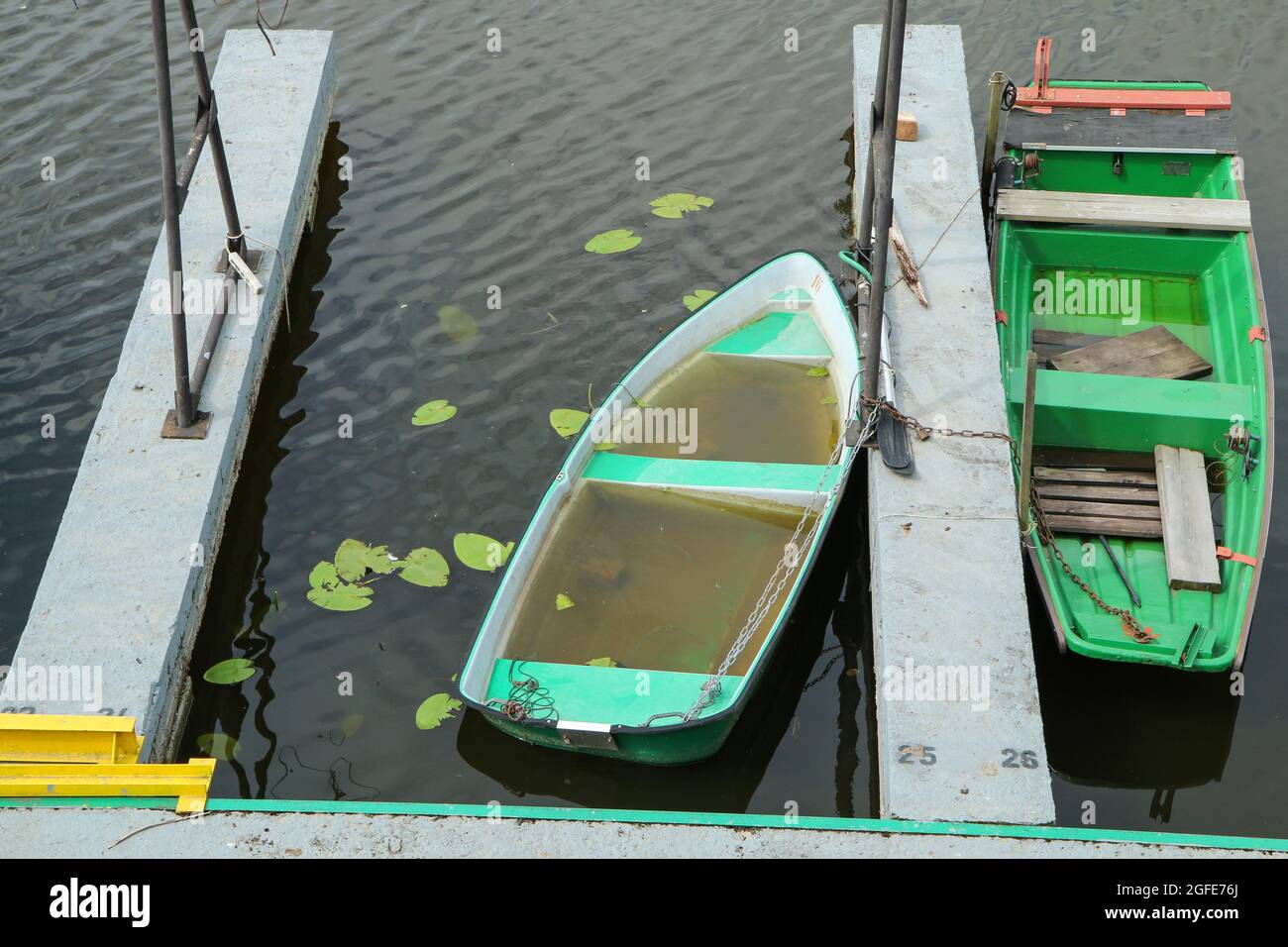 Le vecchie barche di pescatori fluviali sono legate dal molo e inutilizzate. Alcuni di loro pieni di acqua. Foto Stock
