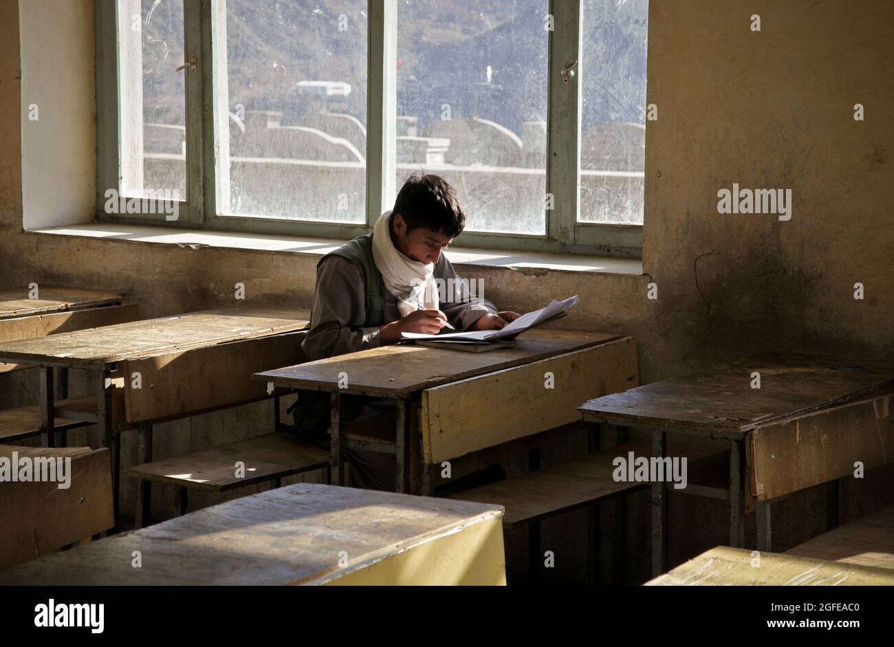 Uno studente afghano legge il suo assegnamento in una scuola superiore nel distretto di Rokha nella provincia di Panjshir, Afghanistan, gennaio 11. Foto Stock