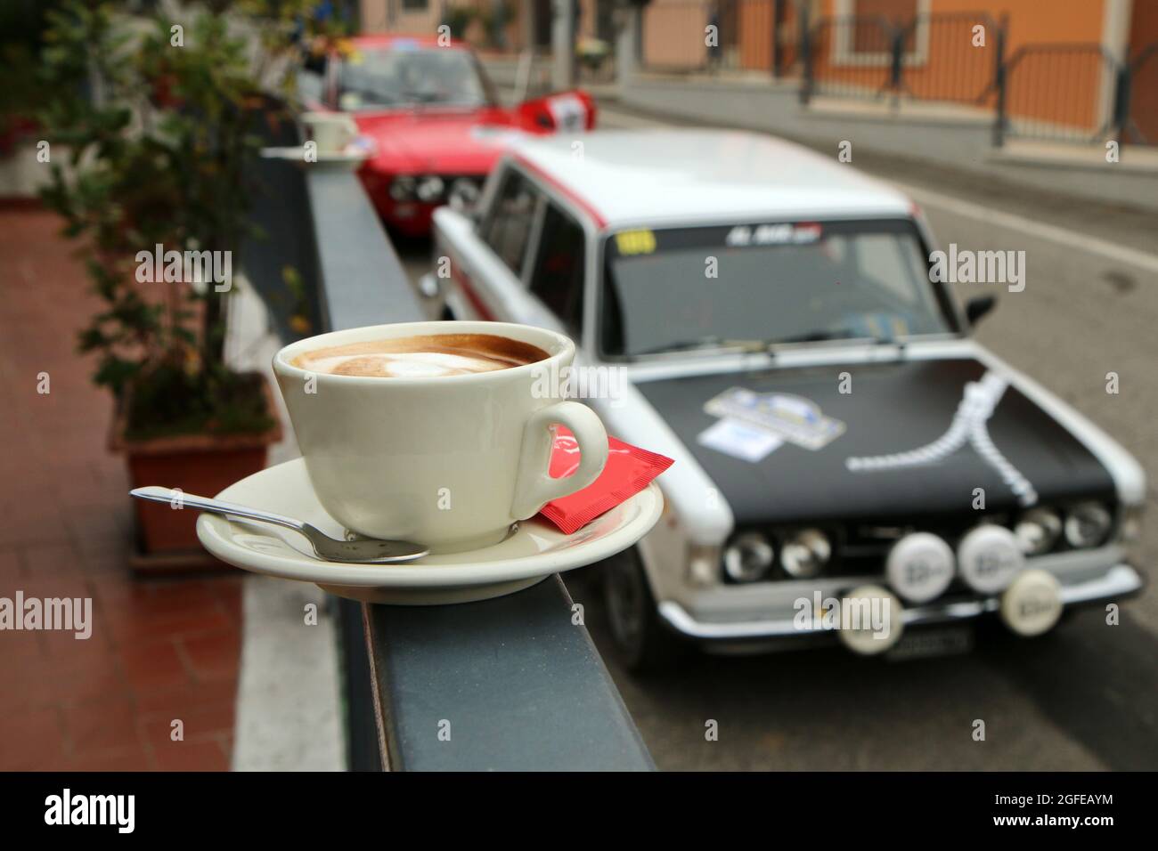 Il tradizionale e gustoso caffè italiano con alcune classiche auto rallye in background. La pausa mattutina durante l'evento. Foto Stock