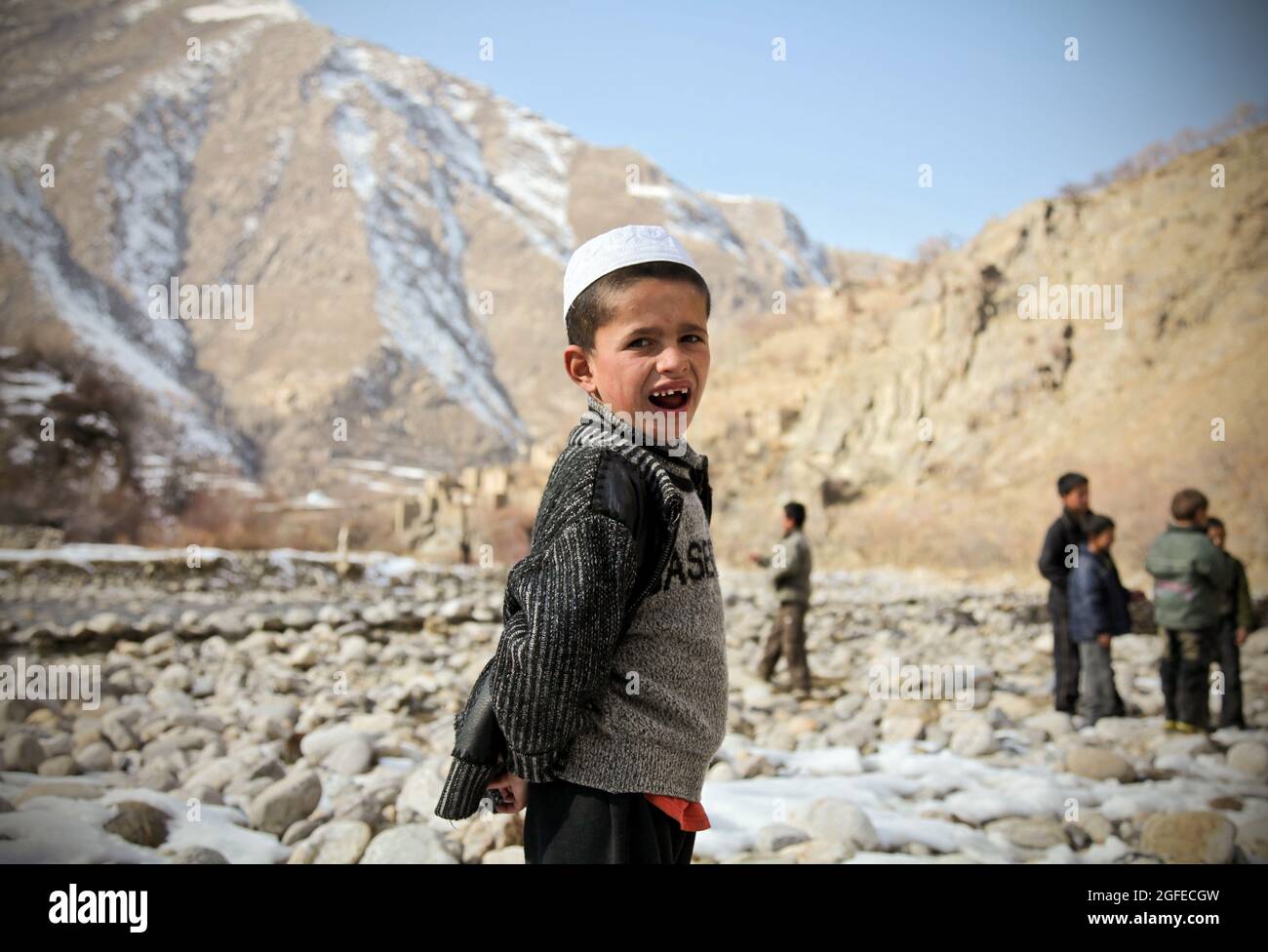 Un bambino afghano sorride giocando accanto al fiume nel distretto di Dara della provincia di Panjshir, Afghanistan, 3 gennaio 2010. Foto Stock