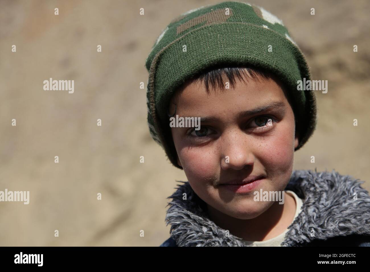 Un bambino afghano sorride giocando accanto al fiume nel distretto di Dara della provincia di Panjshir, Afghanistan, 3 gennaio 2010. Foto Stock
