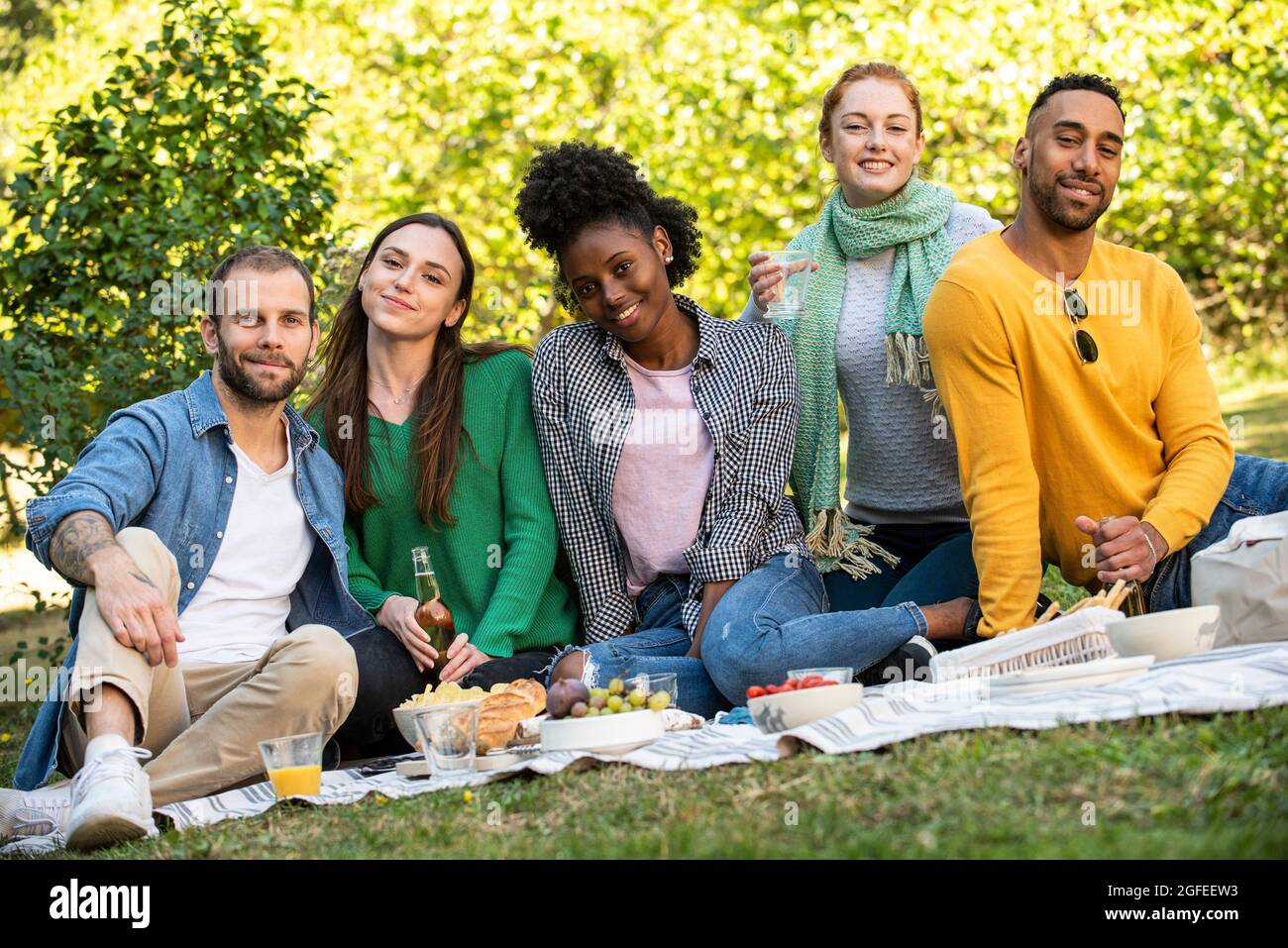 Portrait of smiling young friends having picnic in public park Foto Stock