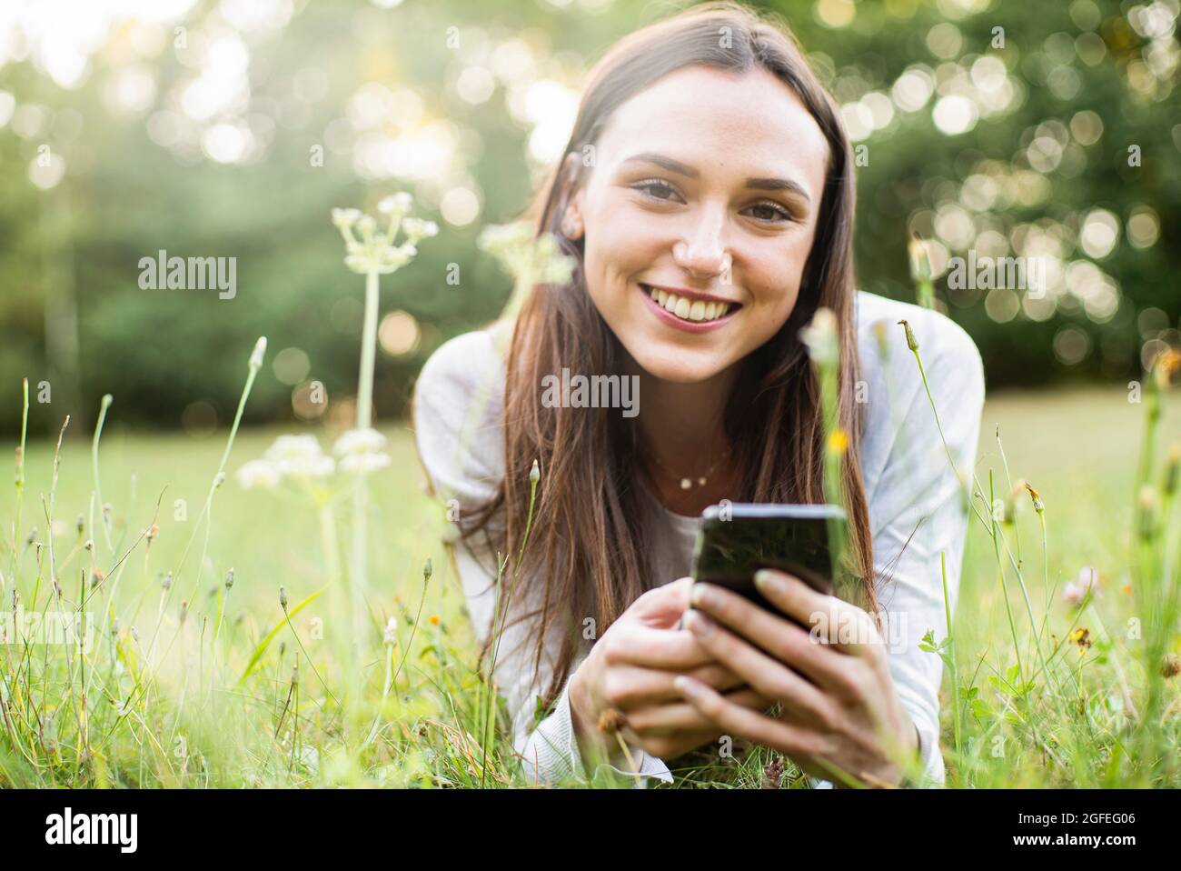 Ritratto della giovane donna che usa lo smartphone mentre si trova nel parco Foto Stock
