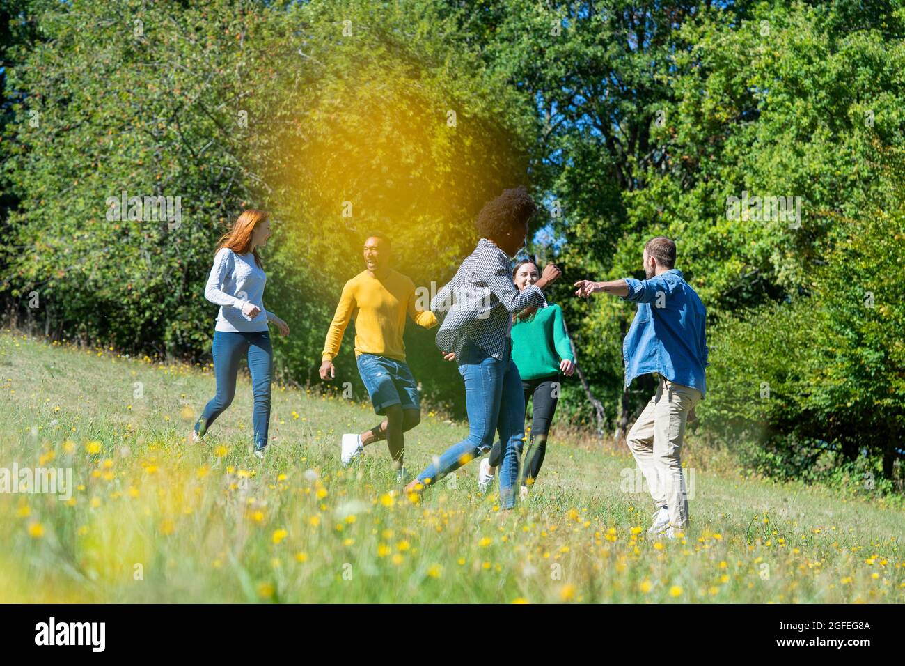 Amici giovani felici che si divertono mentre corrono insieme nel parco Foto Stock
