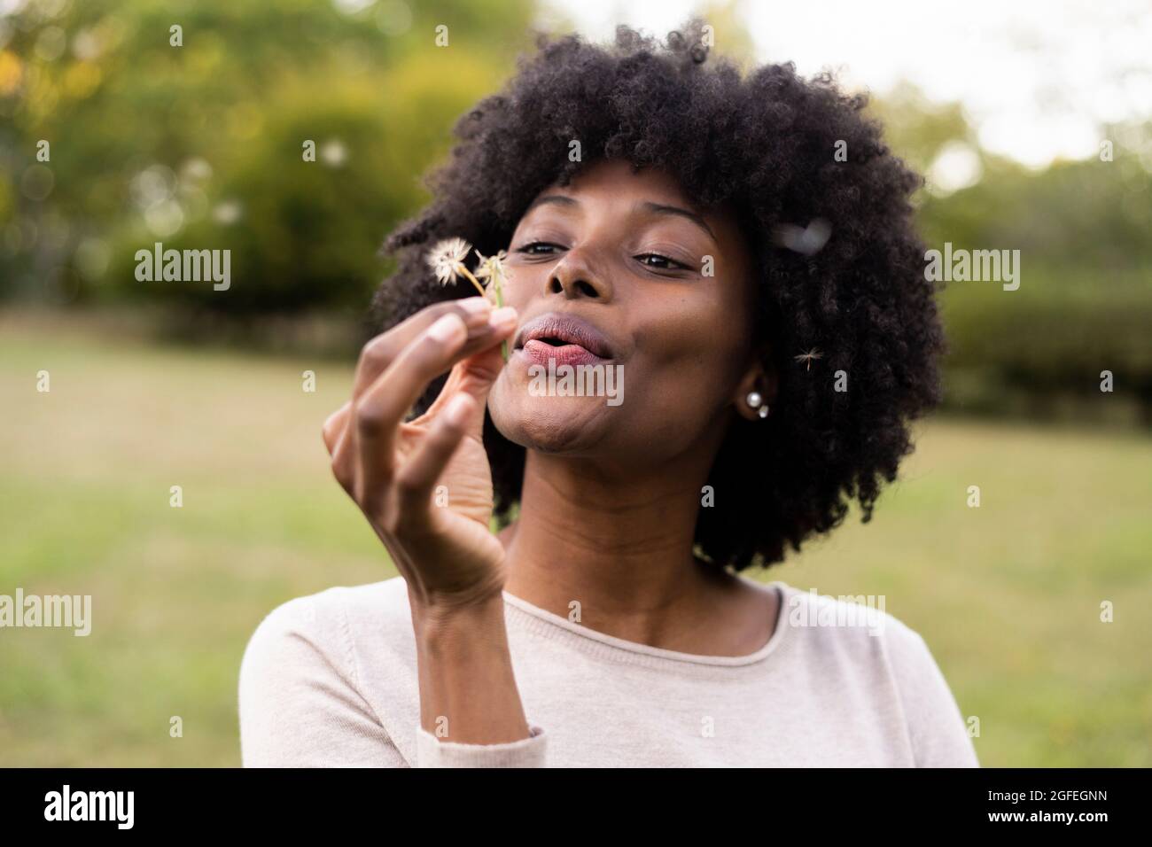 Giovane donna di soffiaggio fiore di dente di leone Foto Stock