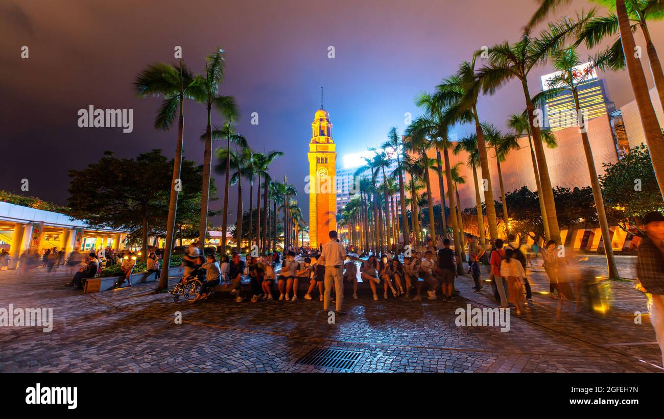 Gruppo di persone sedute vicino alla Torre dell'Orologio di Kowloon, Tsim Sha Tsui Foto Stock