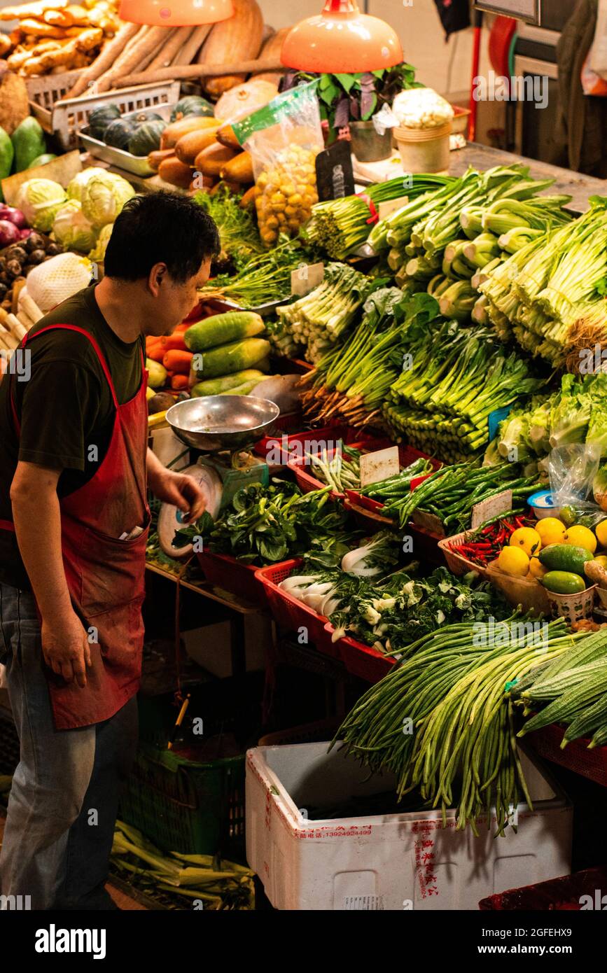 Uomo che vende verdure nel mercato, Macao Foto Stock