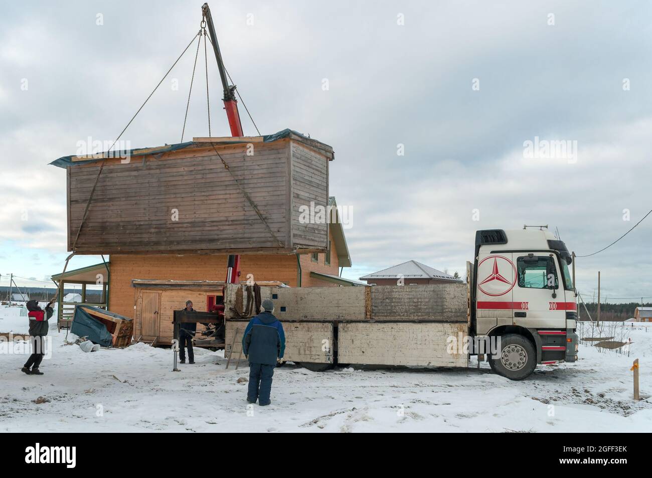 REGIONE DI LENINGRAD, RUSSIA - 04 MARZO 2021: Caricamento di una casa di costruzione su un camion con una gru-manipolatore coperto pomeriggio di marzo Foto Stock