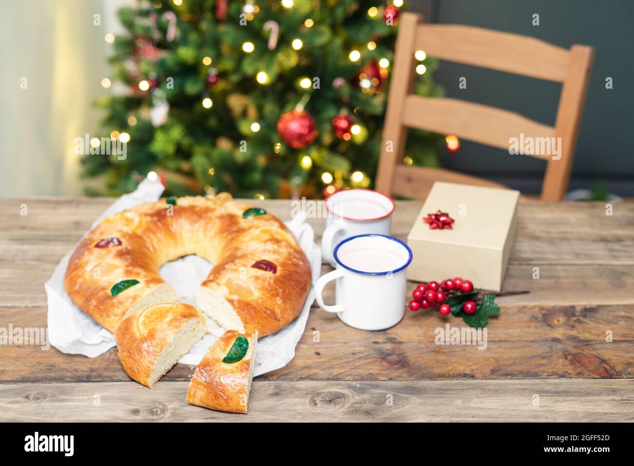 Roscón de Reyes (dolce tipico spagnolo) tagliato, su un tavolo di legno e  albero di Natale con luci sullo sfondo. Dolci e dessert di Natale Foto  stock - Alamy
