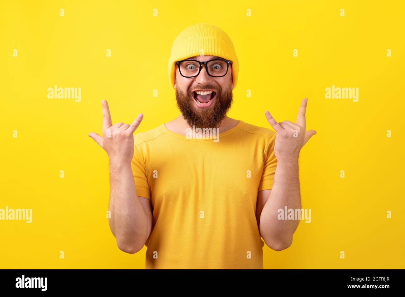 l'uomo divertente fa il movimento del rock n roll su sfondo giallo Foto Stock