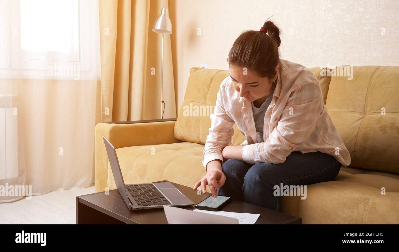 La donna sconvolto cerca di calcolare alti pagamenti sul telefono cellulare Foto Stock