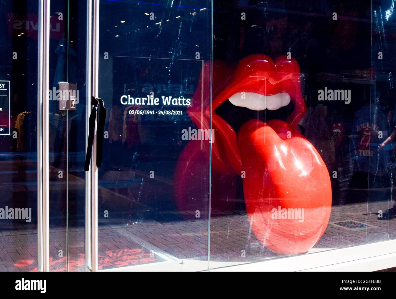 Londra, Regno Unito. 25 ago 2021. Un nastro nero è visto legato alla porta accanto ad un tributo a Charlie Watts e una scultura del famoso logo Tongue and Lips presso il negozio Rolling Stones in Carnaby Street. Il batterista del leggendario gruppo rock The Rolling Stones morì il 24 agosto 2021, all'età di 80 anni. (Foto di Vuk Valcic/SOPA Images/Sipa USA) Credit: Sipa USA/Alamy Live News Foto Stock