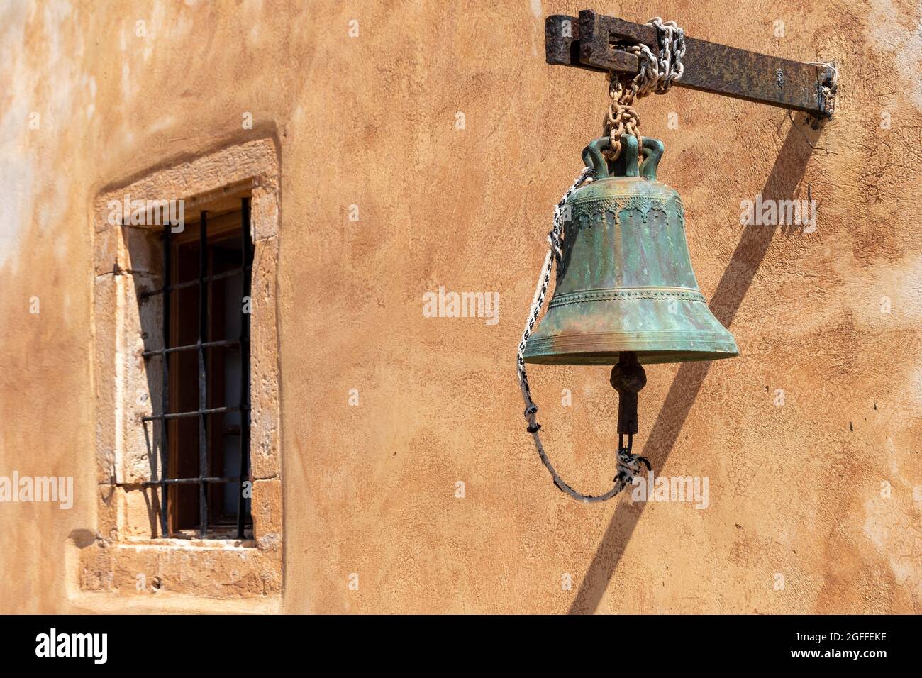 Una campana storica di fronte ad un muro mediterraneo Foto Stock